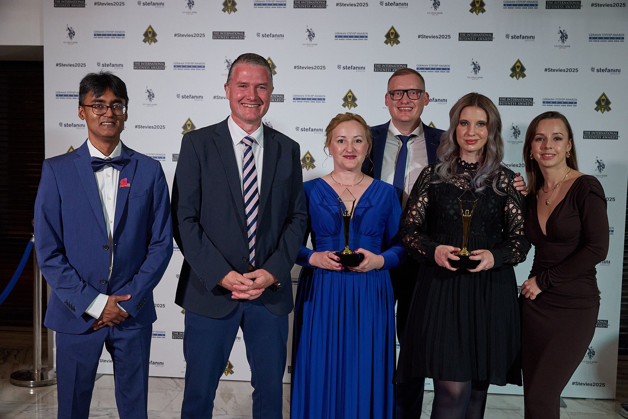 Grupo de ganadores en la alfombra roja de los International Business Awards® 2025 sosteniendo trofeos Stevie de oro