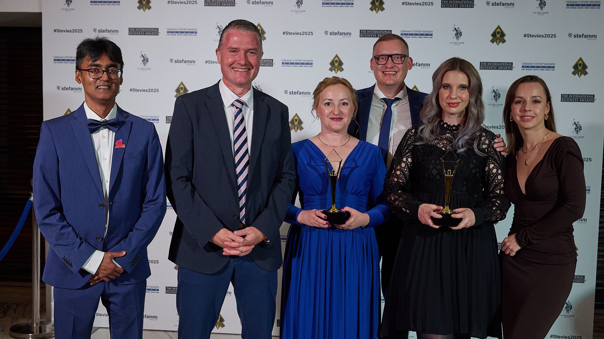 Grupo de ganadores en la alfombra roja de los International Business Awards® 2025 sosteniendo trofeos Stevie de oro