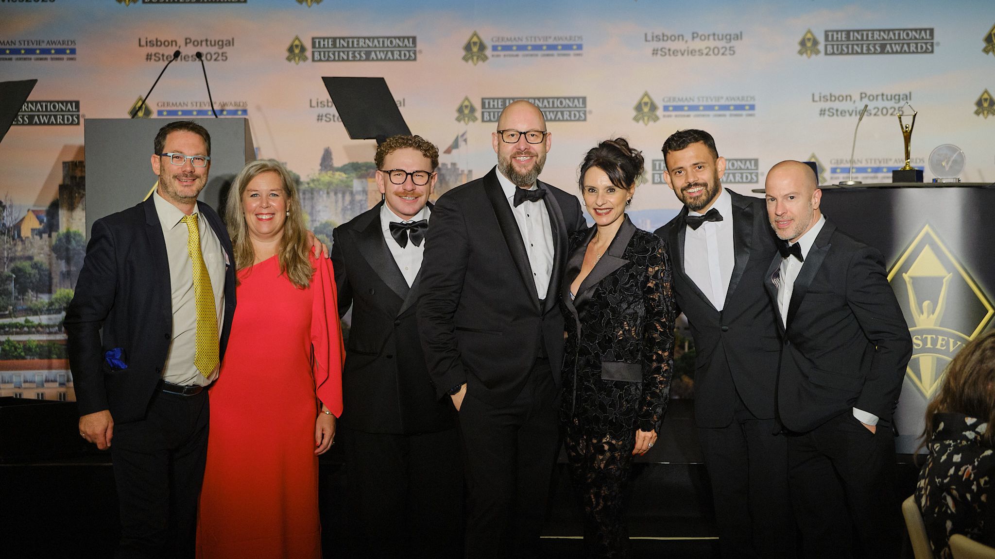 Grupo de ganadores en traje de gala posando en la gala de los International Business Awards® 2025 en Lisboa