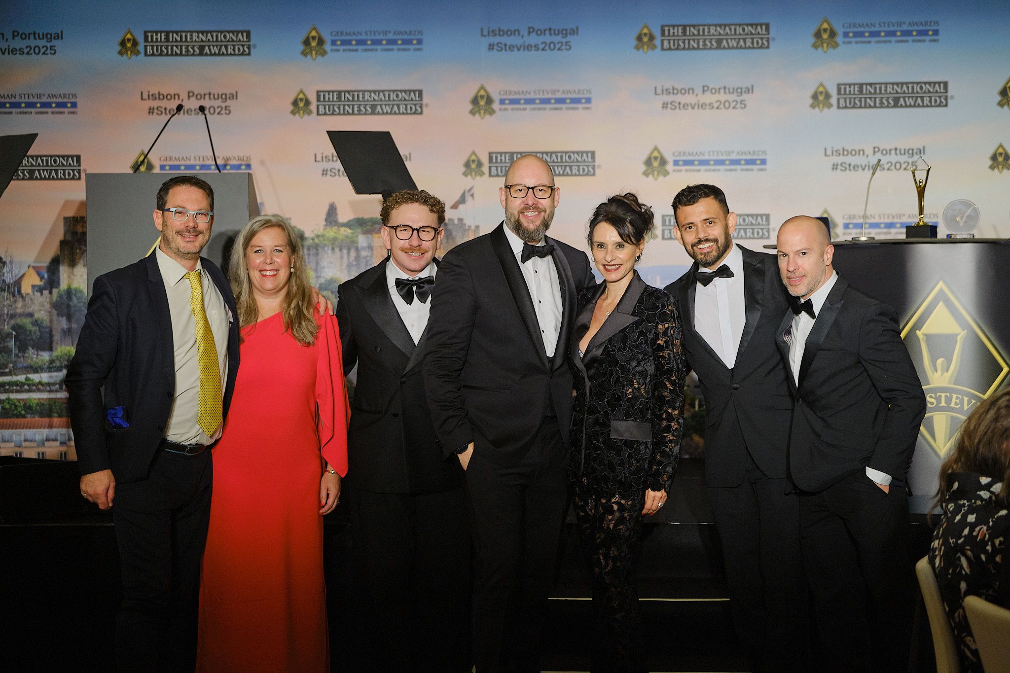Grupo de ganadores en traje de gala posando en la gala de los International Business Awards® 2025 en Lisboa