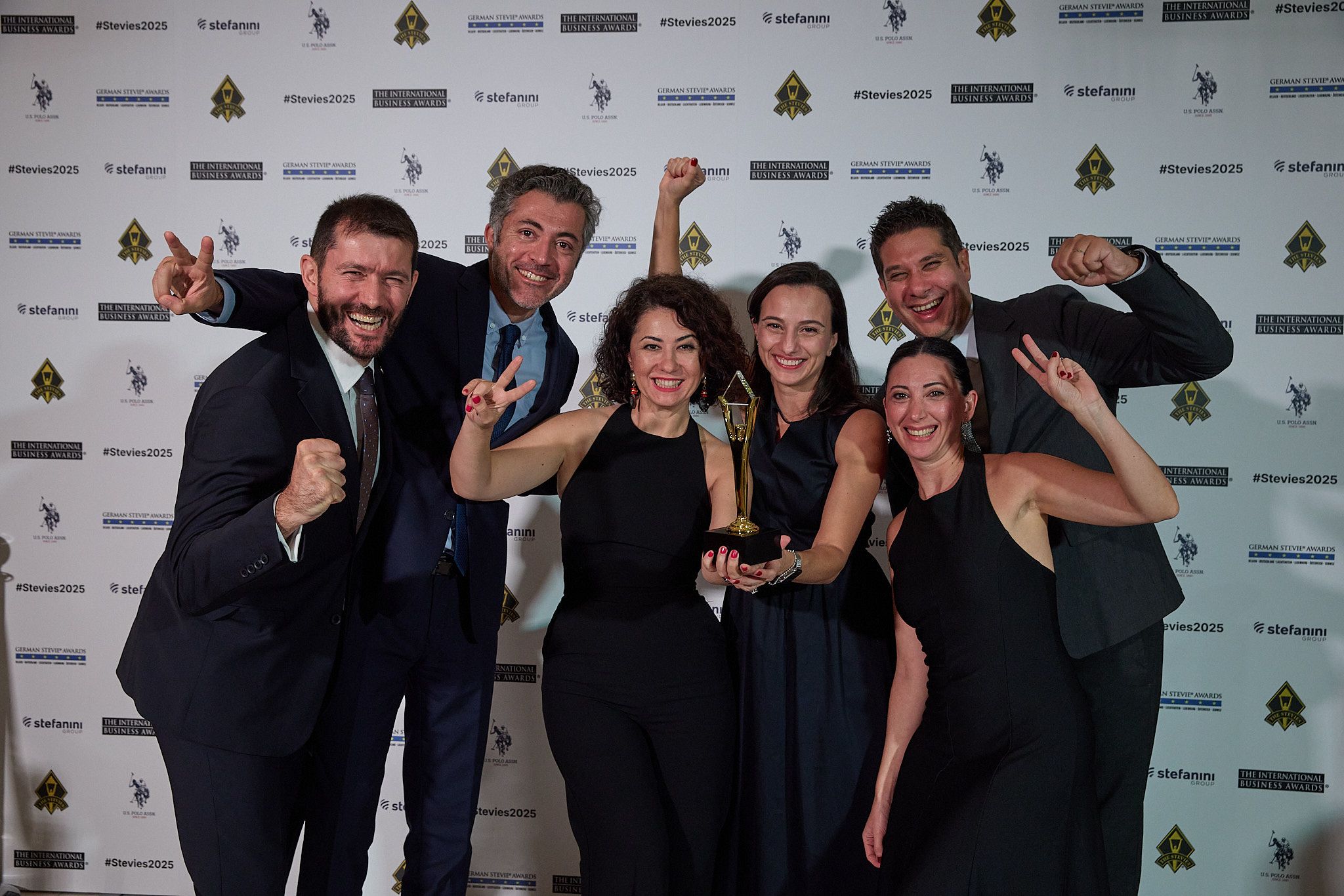 Equipo de ganadores celebrando con su trofeo Stevie en la alfombra roja de los International Business Awards® 2025