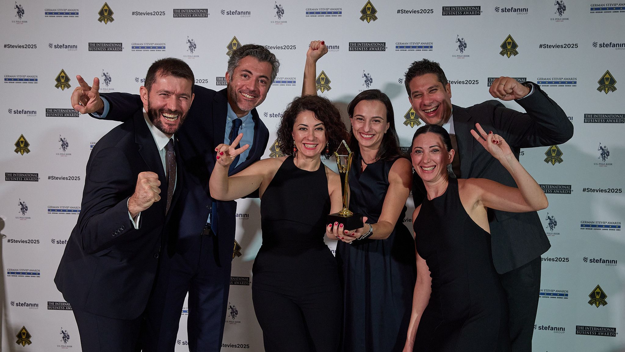 Equipo de ganadores celebrando con su trofeo Stevie en la alfombra roja de los International Business Awards® 2025