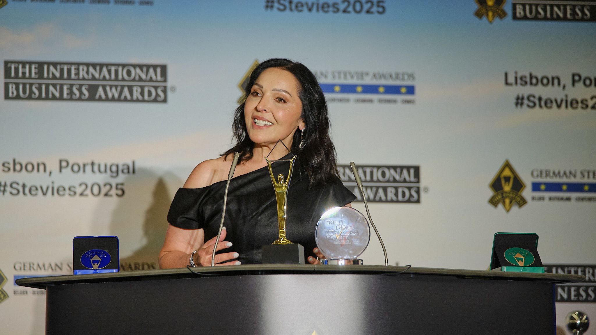 Ganadora sonriente sosteniendo su trofeo Stevie de oro en la alfombra roja de los International Business Awards® 2025