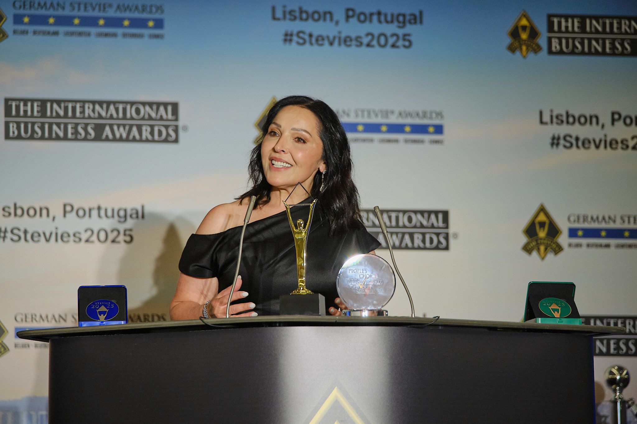 Ganadora sonriente sosteniendo su trofeo Stevie de oro en la alfombra roja de los International Business Awards® 2025