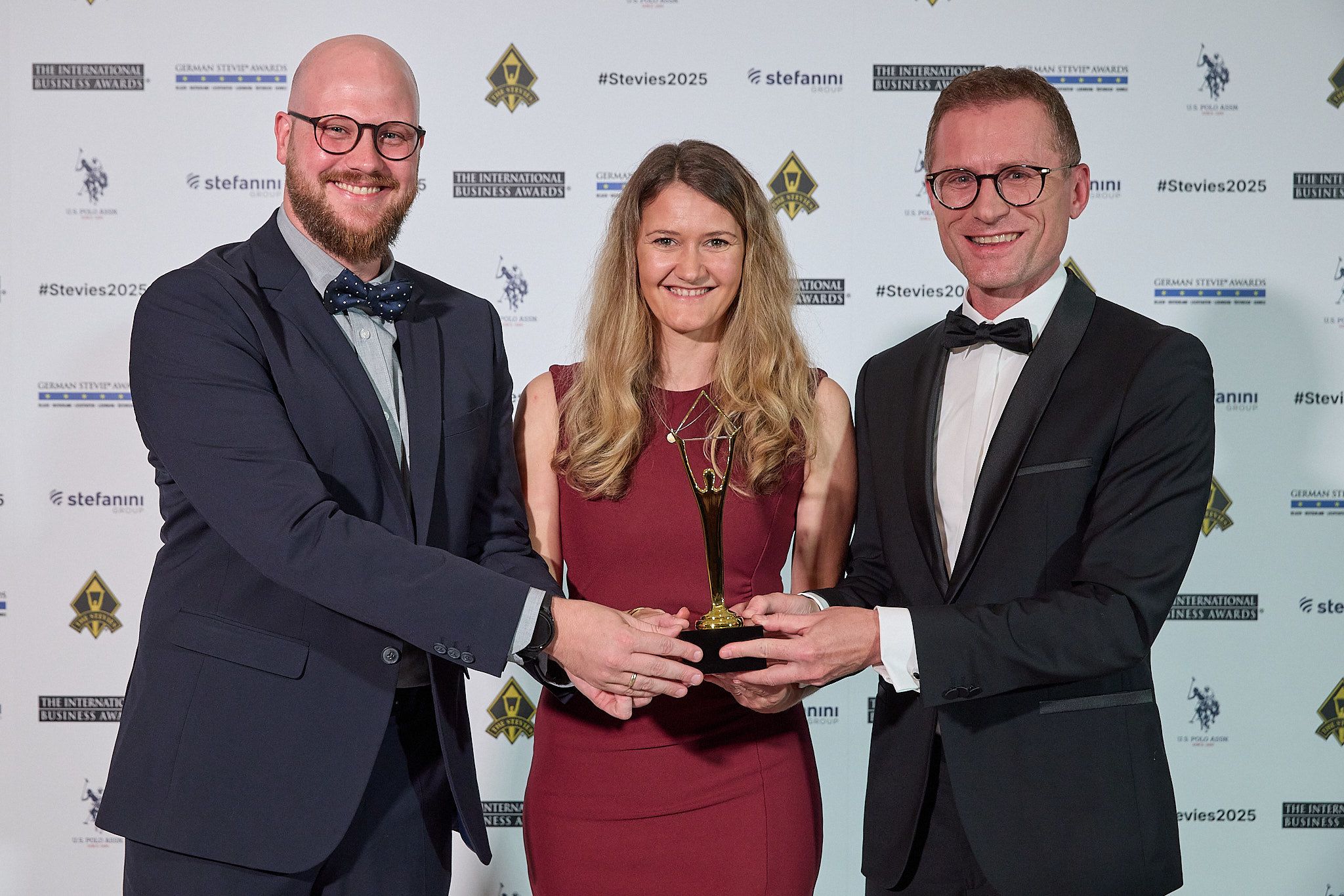Ganadora con vestido de gala sosteniendo su trofeo Stevie en el atril de los International Business Awards® 2025