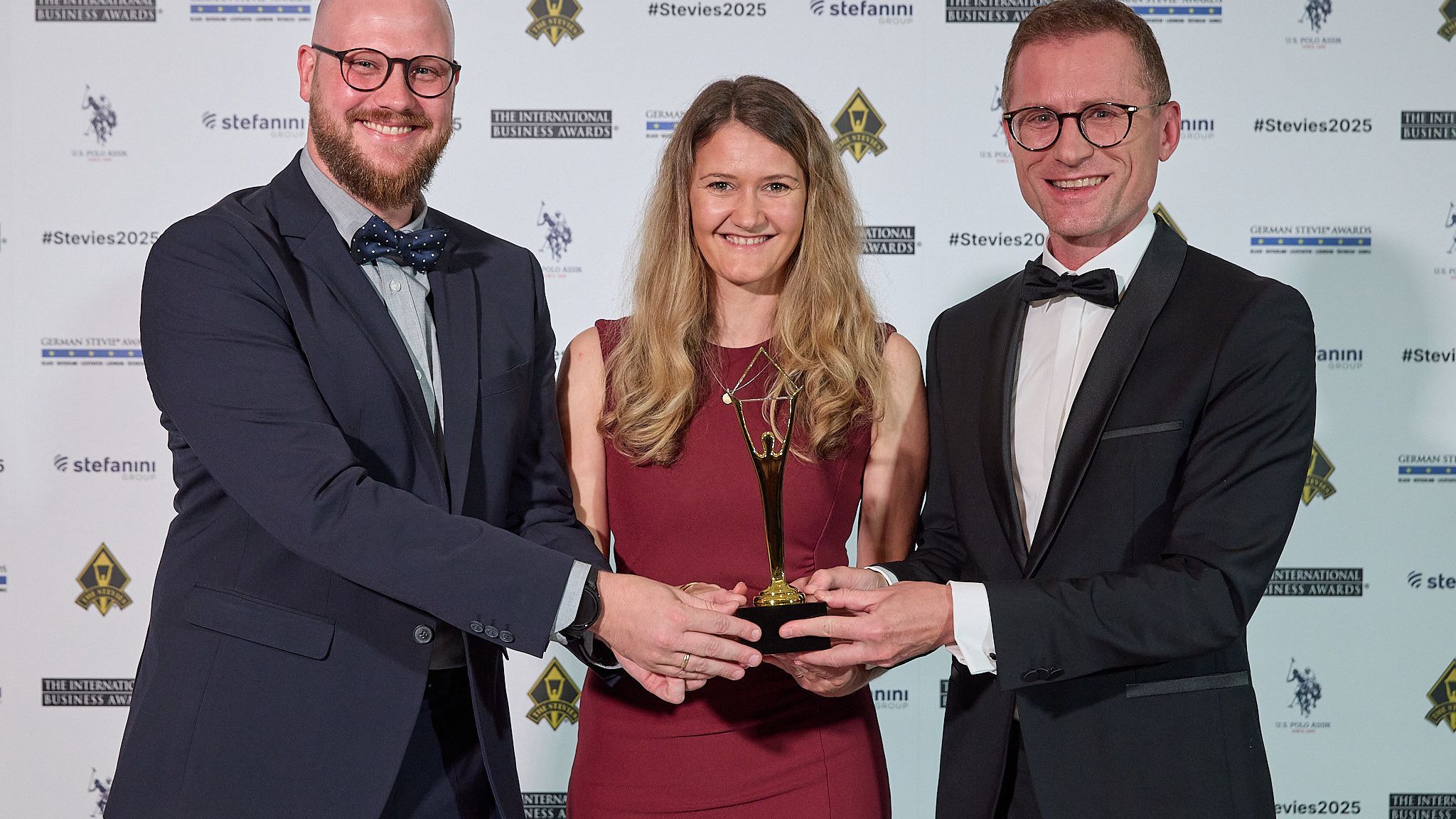 Ganadora con vestido de gala sosteniendo su trofeo Stevie en el atril de los International Business Awards® 2025
