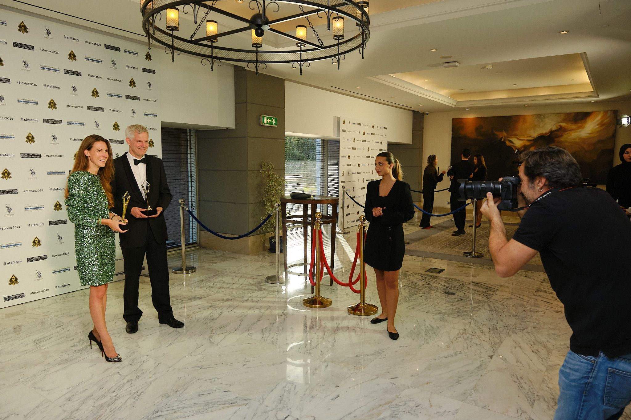 Ganador con traje claro sosteniendo su trofeo Stevie de oro en el escenario de los International Business Awards® 2025