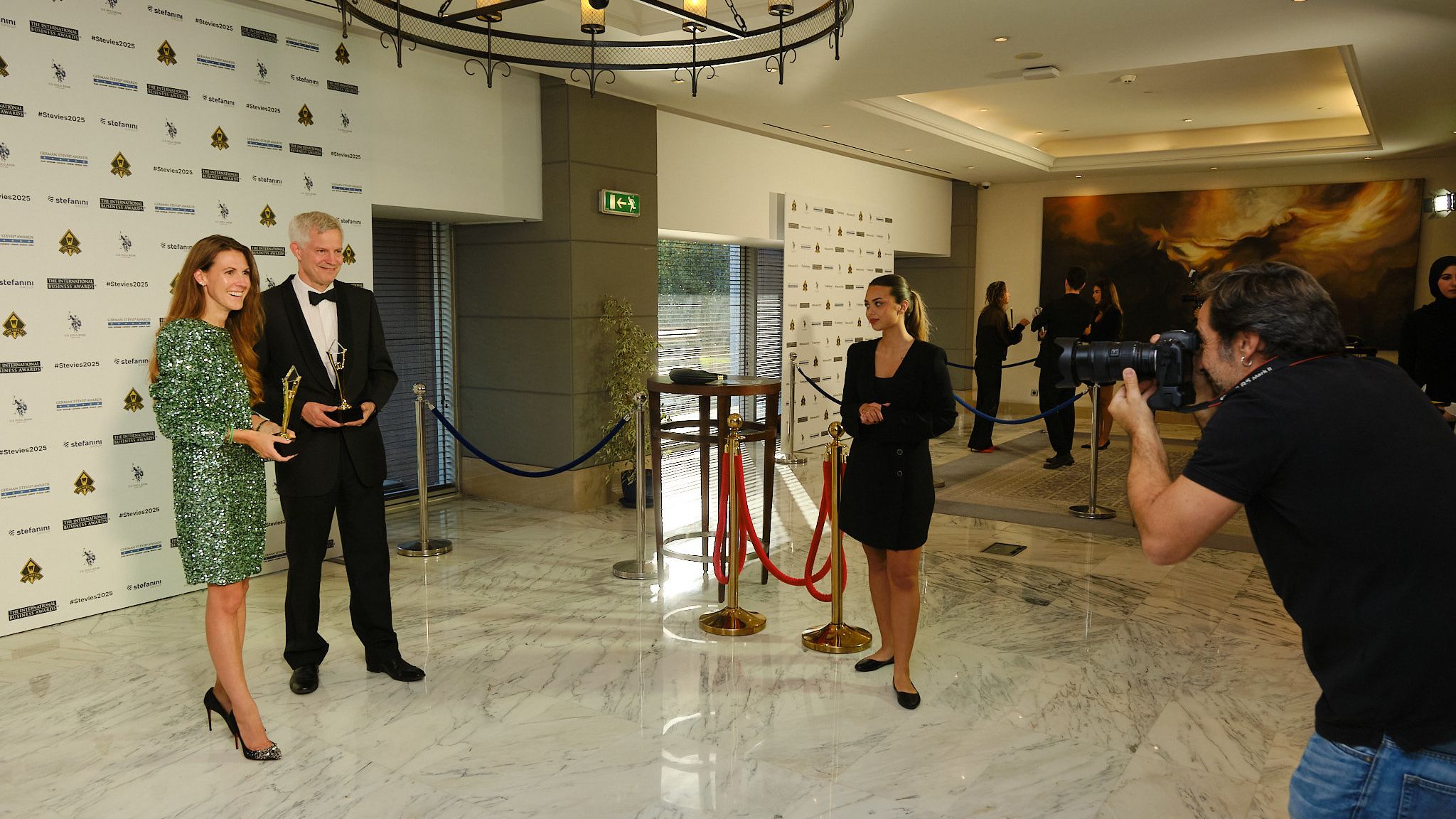 Ganador con traje claro sosteniendo su trofeo Stevie de oro en el escenario de los International Business Awards® 2025