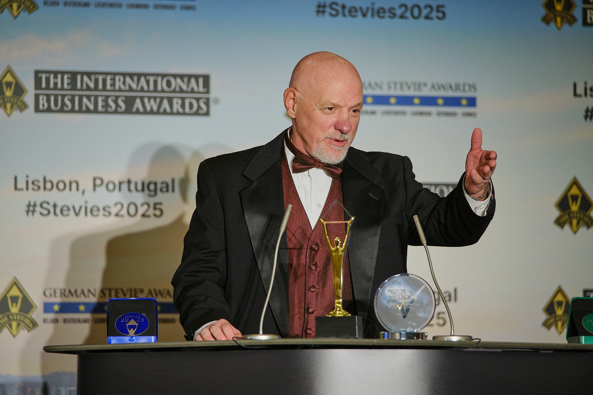 Ganador en esmoquin dando su discurso de agradecimiento en el atril de los International Business Awards® 2025