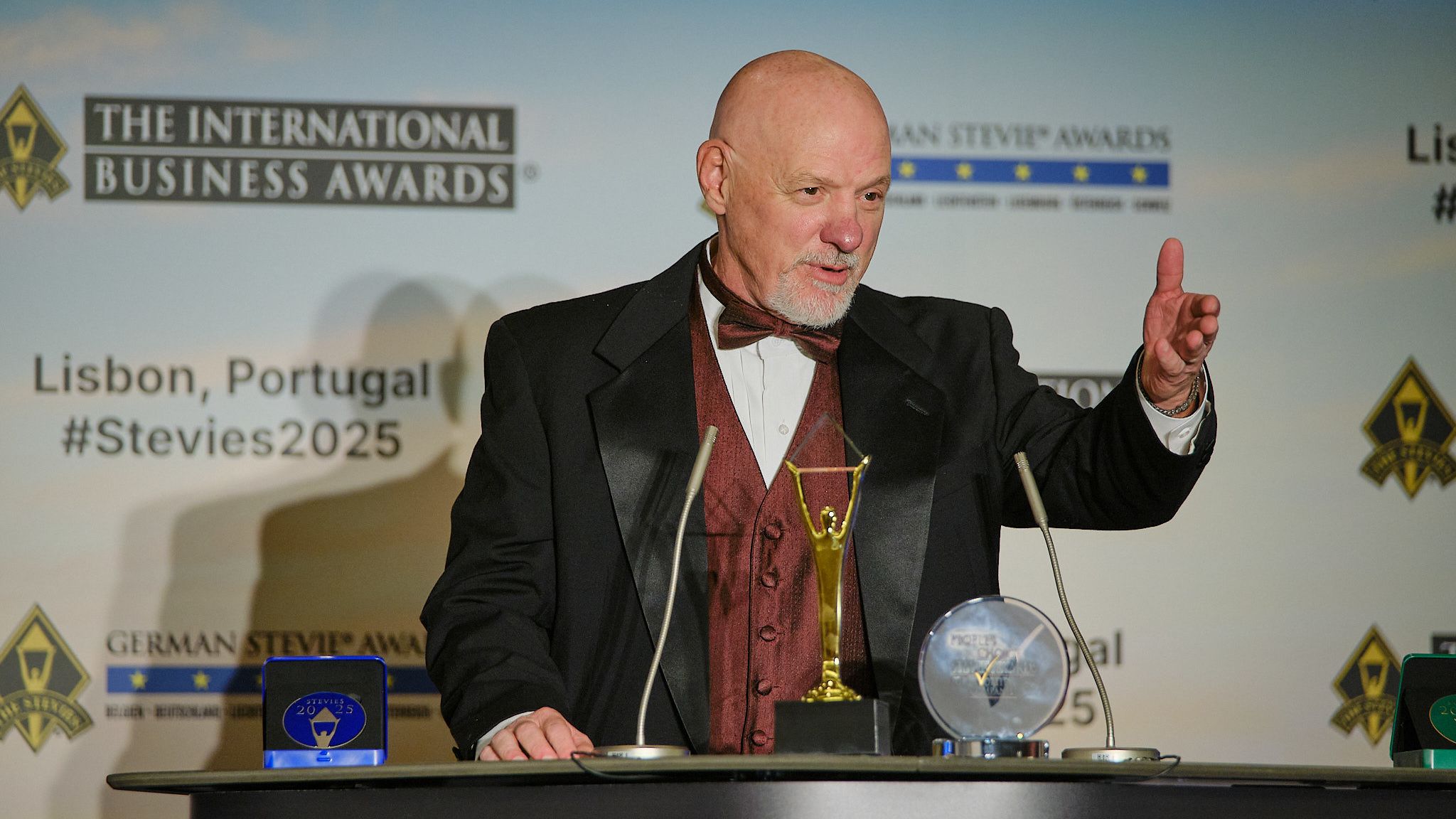 Ganador en esmoquin dando su discurso de agradecimiento en el atril de los International Business Awards® 2025