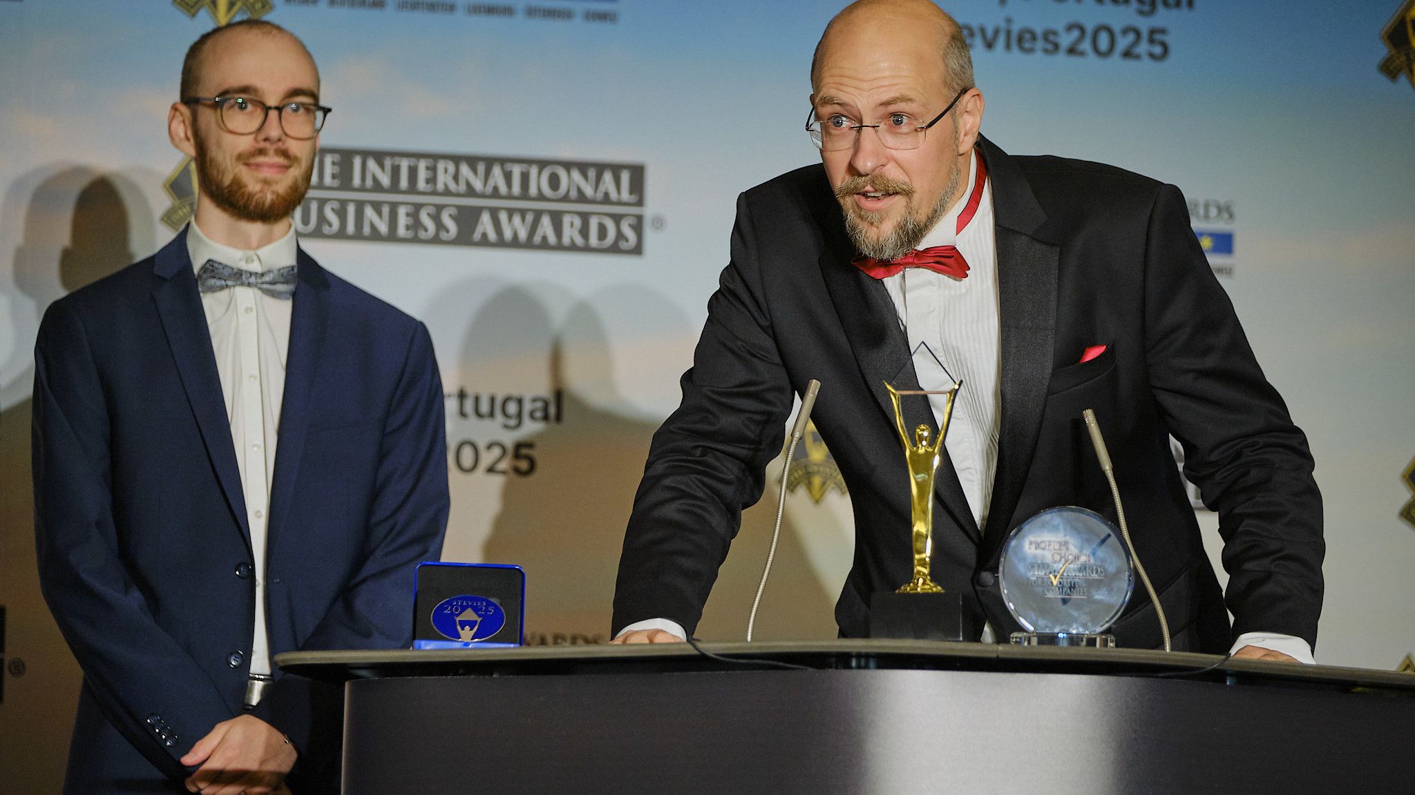Ganador pronunciando su discurso de agradecimiento junto a otro galardonado en los International Business Awards® 2025